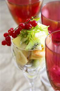 Fruit salad with lime zest in wine glass