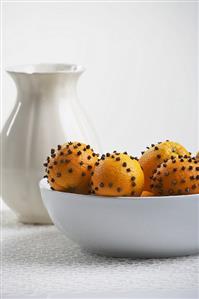 Oranges studded with cloves in porcelain bowl