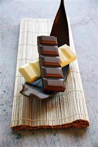 Pieces of white and dark chocolate on piece of cocoa pod