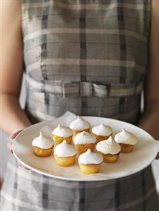 Girl holding a plate of lemon meringue tartlets