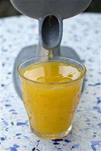 Freshly squeezed orange juice dripping from a juicer