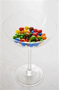 Different coloured chocolate-coated peanuts in a glass