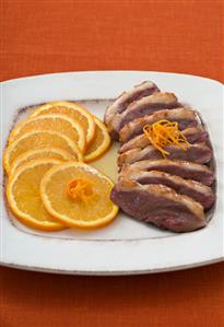 Sliced duck breast with orange slices