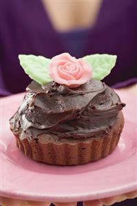 Small cake with chocolate cream and marzipan rose