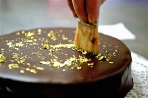 Decorating a chocolate cake with gold leaf
