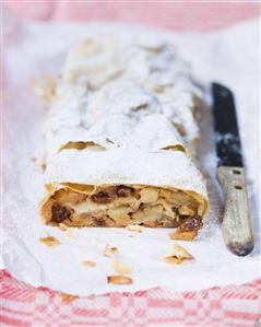 Apple strudel with a slice removed, on paper
