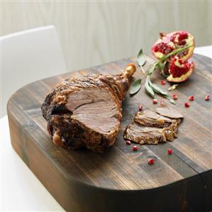 Roast leg of lamb and pomegranate on wooden table