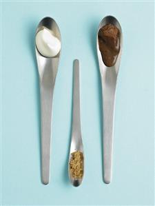 Chocolate sauce, cream and sugar on spoons (overhead view)