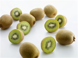 Several kiwi fruits, whole and halved