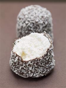 Chocolate teacakes covered in grated coconut (one partly eaten)