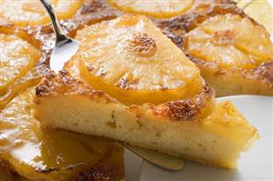 Pineapple upside-down cake, a piece on server (close-up)