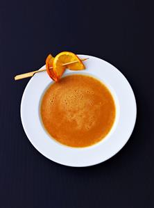 Cream of lentil soup with orange slice on cocktail stick