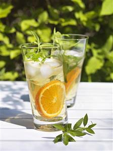 Drinks with lemon verbena and orange slices on table