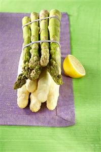 A bundle of green and white asparagus, lemon beside it