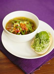 Vegetable soup and bread roll topped with pesto