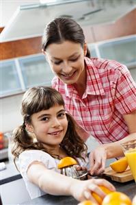 Mother and daughter squeezing oranges in a kitchen