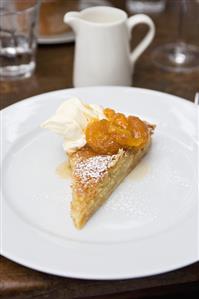 A piece of almond tart with apricots and cream