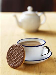 A cup of coffee with a chocolate biscuit