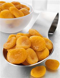 Dried apricots on a spoon and in a bowl