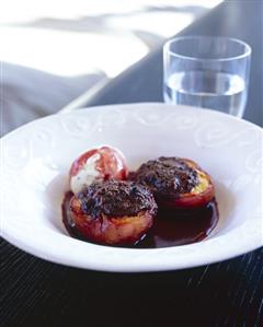 Stuffed, baked peaches in red wine sauce with vanilla ice cream