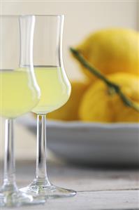 Two glasses of limoncello, lemons in background