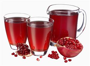 Pomegranate juice in jug & two glasses, fresh pomegranate