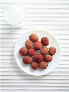 Several unpeeled lychees on plate (overhead view)