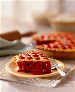 Cherry Pie Slice with Whole Pie in Background