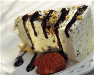 A Slice of Mousse Cake with Chocolate Sauce Nuts and Strawberries