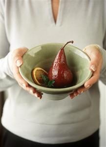 Woman holding bowl of pears in red wine