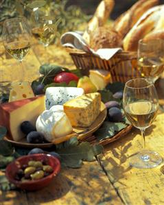 Cheese platter with fruit, olives, bread & wine in open air