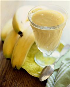 Banana Pudding in a Parfait Glass on a Small Dish with Spoon and Bunch of Bananas