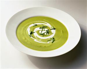 Creamy Pea Soup with Cream Swirl and Chive Garnish in a White Bowl; White Background