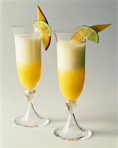 Two Champagne Cocktails with Fruit Garnish on a White Background