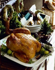 Whole Roast Turkey on a Platter with Figs; Stack of Serving Dishes