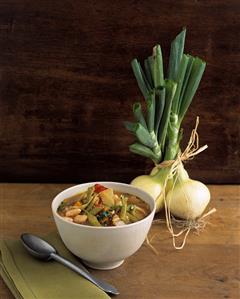 Colourful vegetable stew in bowl, white onions behind