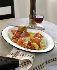 Melon and peach with air-dried ham; red wine glass