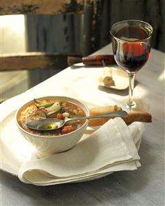 Minestrone on rustic table; red wine glass