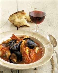 Seafood soup with tomatoes; bread, red wine