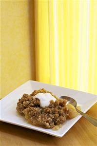 Serving of Apple Cobbler with Whipped Cream on a Plate; Spoon