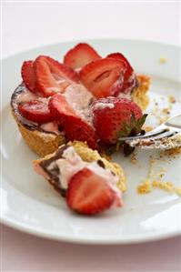 Partially Eaten Strawberry Tartlet on a Plate with a Fork