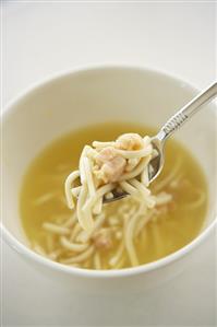 Spoon Scooping Chicken Noodle Soup from a White Bowl