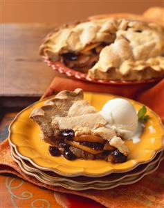 Slice of Apple Raisin Pie with a Scoop of Vanilla Ice Cream on Stacked Plates