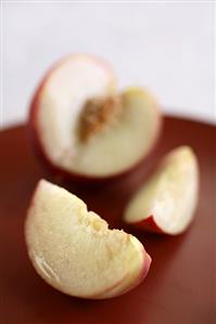 Two Slices of a White Peach with Sliced Peach in Background