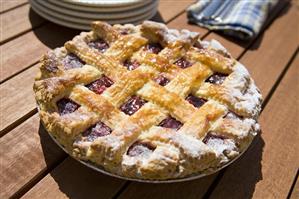 Lattice Top Cherry Pie with Powdered Sugar on Picnic Table