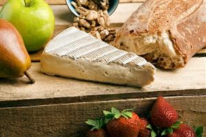 Wedge of Brie Cheese with Fruit and Bread on Wood