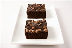 Two Brownies Topped with Chocolate Chips on a White Dish