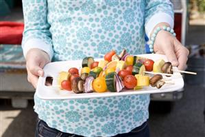 Woman Holding Grilled Fruit and Vegetable Kabobs