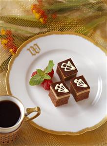 Chocolate Petit Fours on a Plate with Raspberries; Cup of Coffee