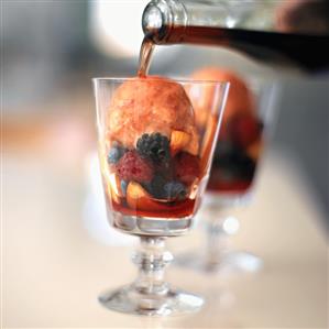 Pouring Red Wine Over Nectarine Sorbet with Fruit in Glass